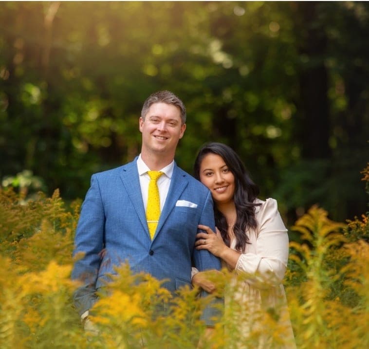 Bradley Griffin in a blue blazer standing with his wife in a field of goldenrod